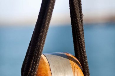 Big wooden pully with brown sailor rope attached on luxury mega yachts for charter.