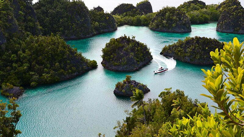 Raja Ampat west Papua ocean is surrounded by hills with a boat in sight